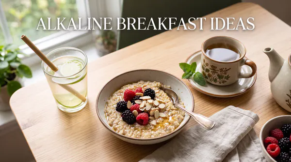 A bright morning breakfast setting featuring a warm bowl of quinoa porridge topped with fresh raspberries and blackberries, alongside a cup of herbal tea and lime water on a rustic table, featuring the text "Alkaline Breakfast Ideas".
Image filename: alkaline-diet-breakfast-ideas.jpg